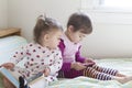 4-year-old girl watching cell phone and 1-year-old girl reading book