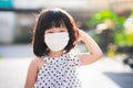 A 4-5 year old girl wears face mask. Sweet smiling child take walk in the morning. Sunlight hits the hair. Rim Light. New normal. Royalty Free Stock Photo