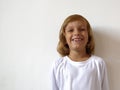 A 6-year-old girl in a white T-shirt is smiling. The hair is cut in a bob style. A child with blond hair and tanned skin. Copy Royalty Free Stock Photo