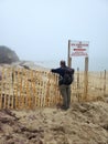 50 year old guy stands at beach fence and Seal Observation sign Royalty Free Stock Photo