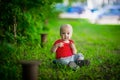 A 2-year-old kid in a bright red T-shirt on a background of green grass. Royalty Free Stock Photo