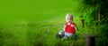 A 2-year-old kid in a bright red T-shirt on a background of green grass. Royalty Free Stock Photo