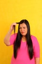 40-year-old Latina woman with long hair suffers from having it mistreated, observes her damaged split ends that need treatment Royalty Free Stock Photo