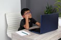 Boy does home schooling takes online classes at home on a desk with a laptop, studies, is surprised and participates in class