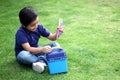 6 year old latino boy sitting on the grass with lunch box and colors for back to school