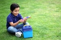 6 year old latino boy sitting on the grass with lunch box and colors for back to school