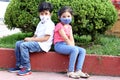 6-year-old Latino boys couple with face masks sitting waiting to play in times of covid-19