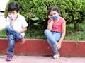 6-year-old Latino boys couple with face masks sitting waiting to play in times of covid-19