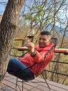 40-year-old Latino man drinks wine on the terrace of his cabin in the woods relaxes in his free time on weekend vacations