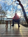 40-year-old Latino man drinks wine on the terrace of his cabin in the woods relaxes in his free time on weekend vacations