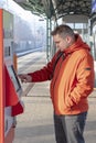 A 25-30-year-old man buys a ticket for city transport in an electronic ticket vending machine at a railway station.