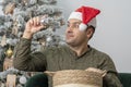 A 30-35-year-old man in a red hat looks at Christmas toys and balls from a wooden basket. Royalty Free Stock Photo