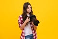 12, 13, 14 year old teen girl holding digital camera or DSLR over yellow background. Royalty Free Stock Photo