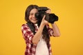 12, 13, 14 year old teen girl holding digital camera or DSLR over yellow background. Happy teenager, positive and Royalty Free Stock Photo