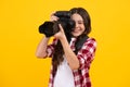 12, 13, 14 year old teen girl holding digital camera or DSLR over yellow background. Happy teenager, positive and Royalty Free Stock Photo