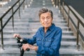 90 year old woman with gray hair, wrinkles, progressive and active uses modern electric transport scooter. Lady Royalty Free Stock Photo