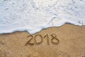 The year 2018 passed the concept. The wave of foam washes away the inscription 2018 written on the sand