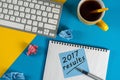 2017 year review on clipboard and coffee against yellow and blue table with keyboard