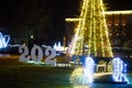 Year 2020 sign with fallen 0 sign in front of Christmas tree