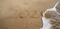 Year 2020 in tet written in sand on beach is covered by ocean wave and disappears