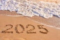 2025 year written on sandy beach sea at sunny day