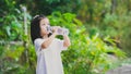 4 years Asian kid drinking water from plastic bottle. Child girl was thirsty. Green nature background.