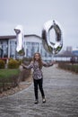 10 years birthday. the girl is holding large silver numbers one and zero. Cute joyful birthday girl with balloons Royalty Free Stock Photo