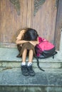 7 or 8 years child in school uniform sitting outdoors crying sad and depressed with her backpack on the stairs suffering bullying Royalty Free Stock Photo