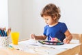 3 years girl painting at the small table at home.