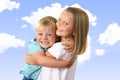 7 years old adorable blond happy girl posing with her little 3 years old brother smiling cheerful isolated on blue sky with clouds Royalty Free Stock Photo