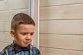 A 4 years old boy in a blue clerical shirt is crying on a light wooden background