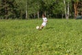 9 years old boy plays soccer in sunny summer day. A child kicks feint with soccer ball, throws it up Royalty Free Stock Photo