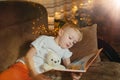 3-4 years old boy is reading a book sitting on a sofa with teddy bear. Home reading of fairy tales. Cute little boy is Royalty Free Stock Photo