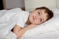 7 years old boy resting in white bed with eyes open Royalty Free Stock Photo