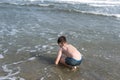 13 years old boy relaxation on the sand on the beach in the sea waves. Concept of family summer vacation Royalty Free Stock Photo