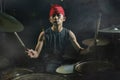 13 or 14 years old cool and talented Asian American mixed ethnicity young boy playing drums in headband performing song in dark