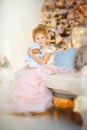 5 years old girl in beautiful light pink dress with doll in blue clothes in christmas time