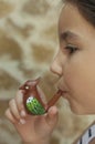 9 years old girl blowing a ceramic water whistle Royalty Free Stock Photo