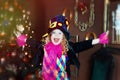 5 years old girl in clown costume with wide smile near christmas tree. Happiness and masquerade in christmas time. Happy child in Royalty Free Stock Photo