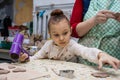 Child girl with a teacher in a pottery workshop.