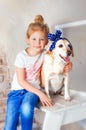 5 years old girl sit on white wooden ladder with her dog. Girl in blue jeans and white t-shirt hug golden dog. Friendship between Royalty Free Stock Photo