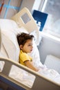 7 years old ill child in yellow t-shirt lying in bed in hospital room after serious nasal surgery. Medical care for children. Royalty Free Stock Photo