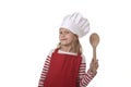 7 years old little girl in cooking hat and red apron playing cook smiling happy holding spoon Royalty Free Stock Photo