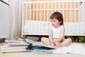 2 years toddler reading books against white bed Royalty Free Stock Photo
