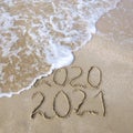 2020, 2021 years written on sandy beach sea. Wave washes away 2020