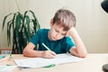 7 yeas old boy sitting at desk and doing homework