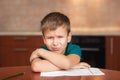 7 yeas old boy sitting at table and crying while working on hard homework