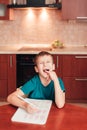 7 yeas old child sitting at table in the kitchen and doing lessons