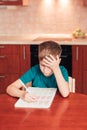 7 yeas old child sitting at table in the kitchen and doing lessons