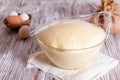 Yeast dough in a glass bowl under cling film on wooden table Royalty Free Stock Photo